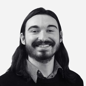 Smiling man with long hair, black sweater.