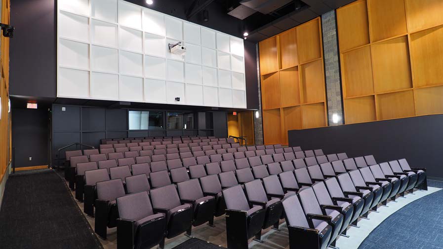 Empty auditorium with rows of purple seats.
