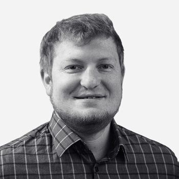 Smiling man in plaid shirt, grayscale photo.