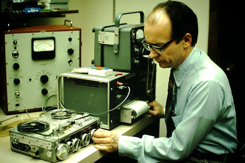 Man operating vintage audio recording equipment.
