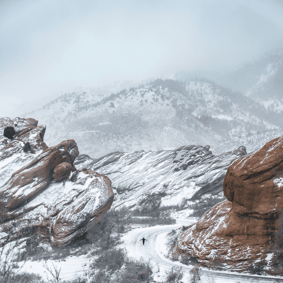 Snow-covered rocky landscape with a lone figure.