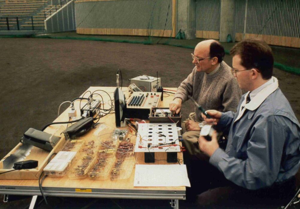Men working with electronic equipment on table.