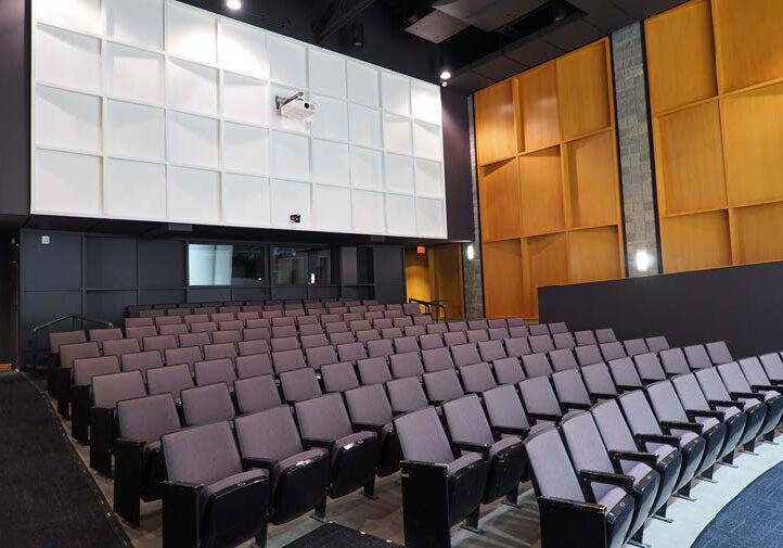 Empty auditorium with rows of purple seats.