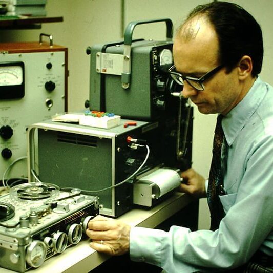 Man operating vintage audio recording equipment.