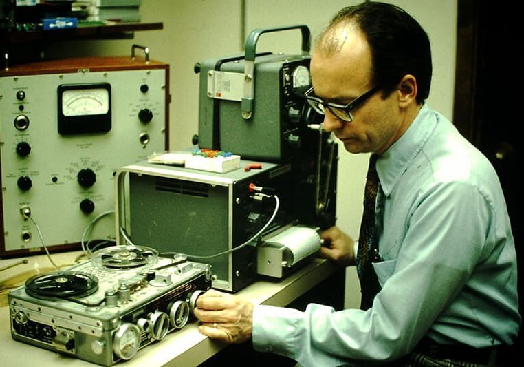 Man operating vintage audio recording equipment.