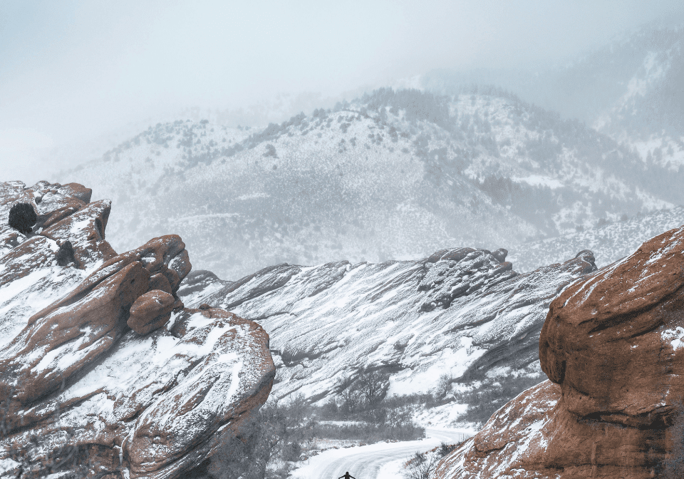Snow-covered rocky landscape with a lone figure.